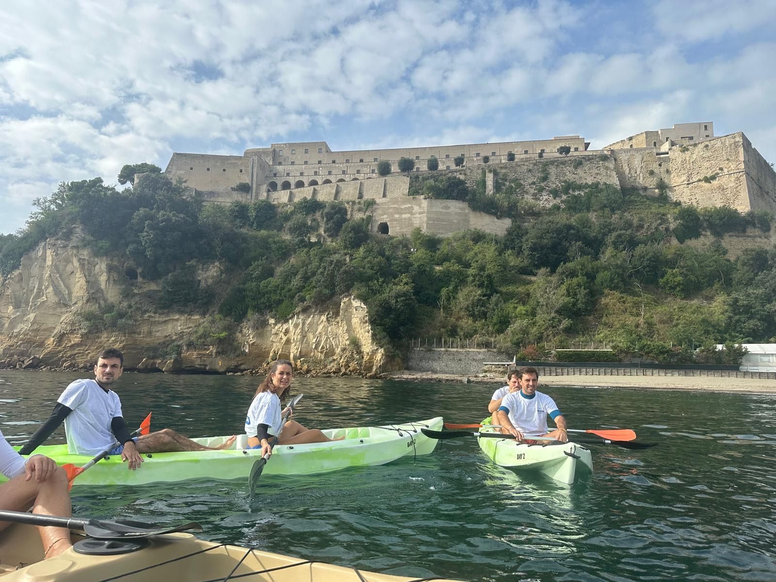 Partecipanti in kayak sotto il Castello di Baia